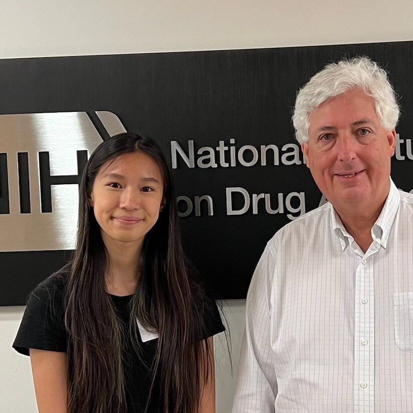 Vivian Lee and Jonathan Pollock pose in front of a large sign for the National Institute on Drug Abuse