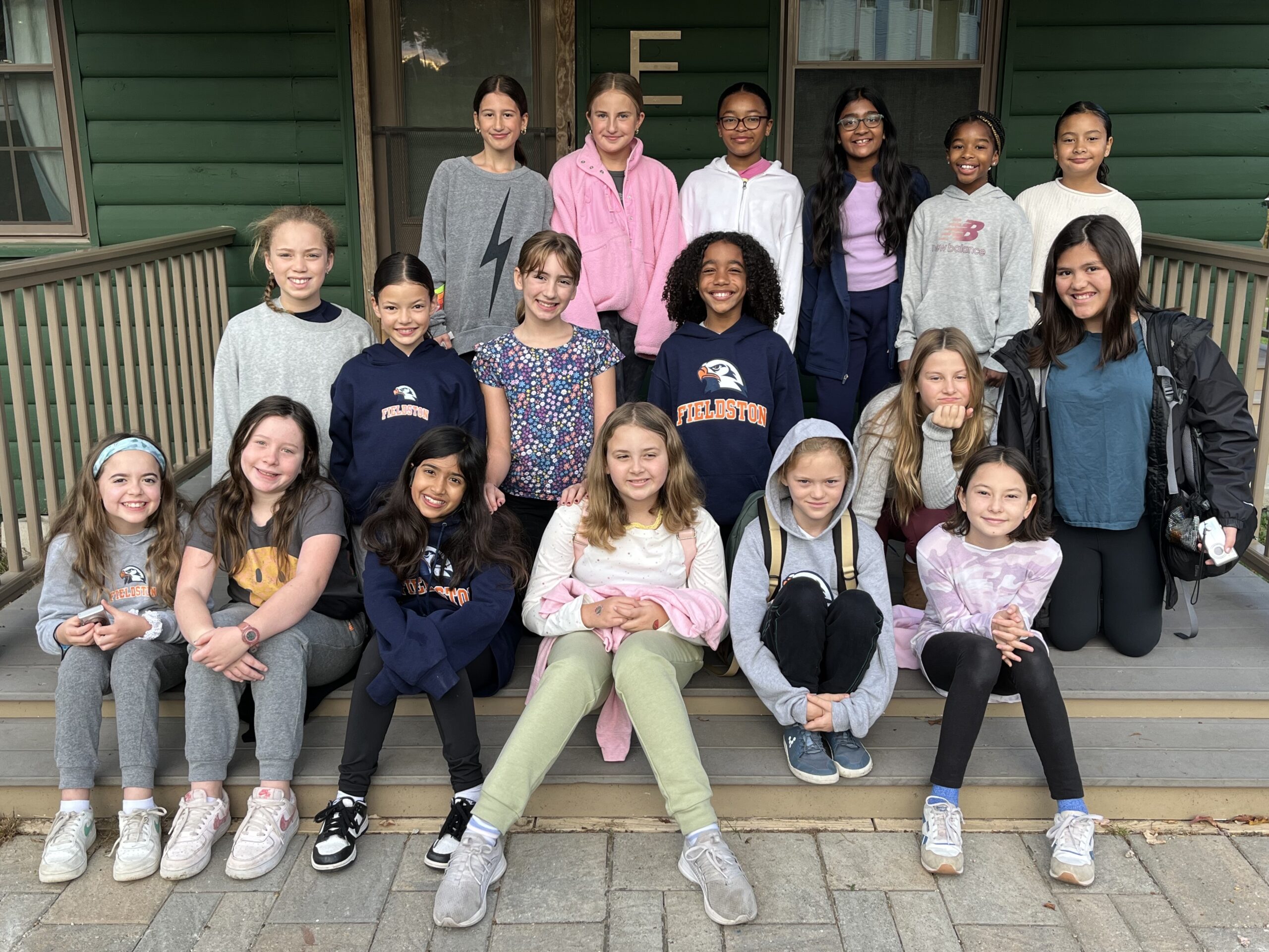 5th Graders from Fieldston Lower pose and smile together outside of cabin at Nature's Classroom.
