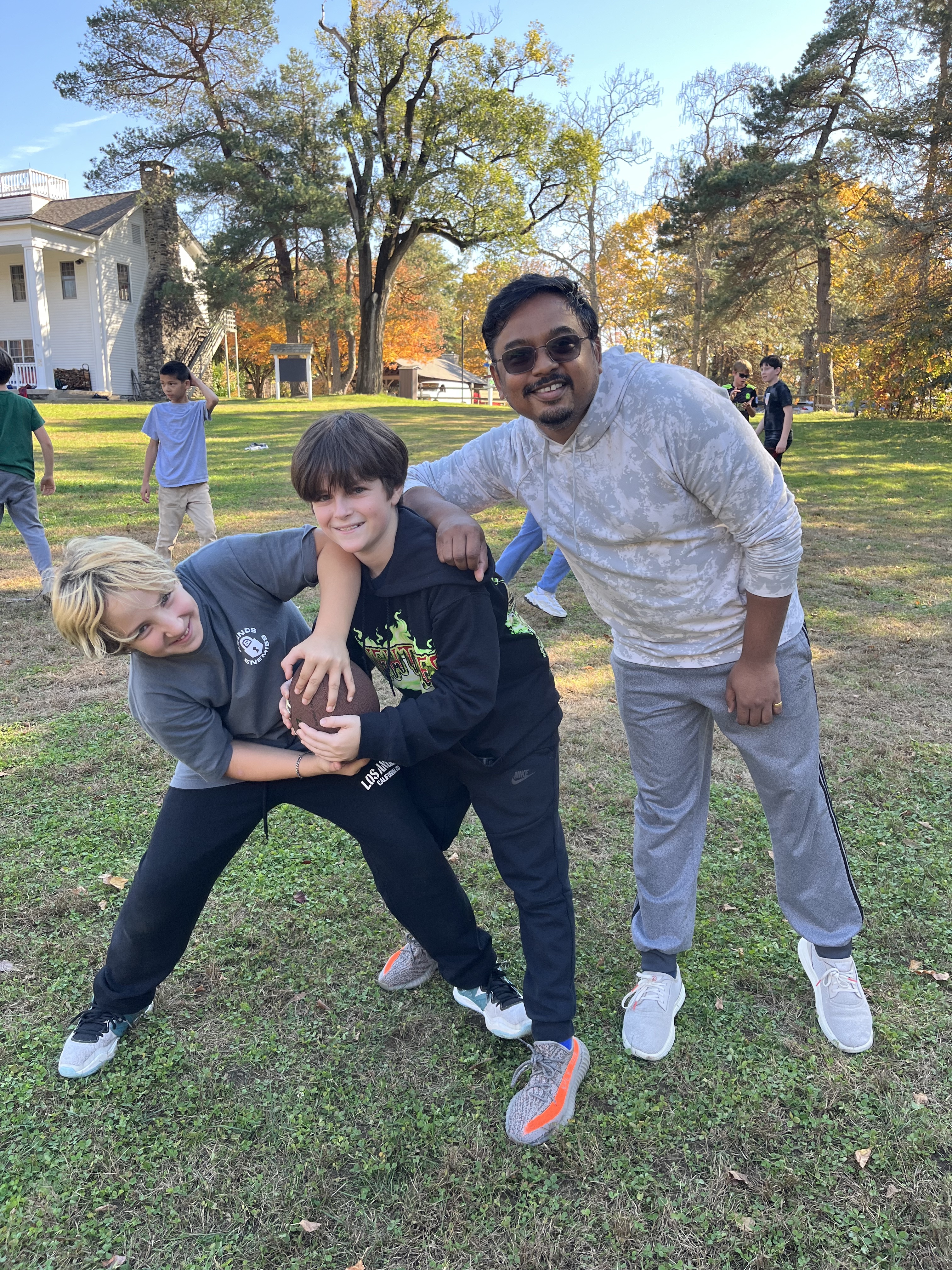Students and Fieldston Lower Assistant Principal pose together with football.