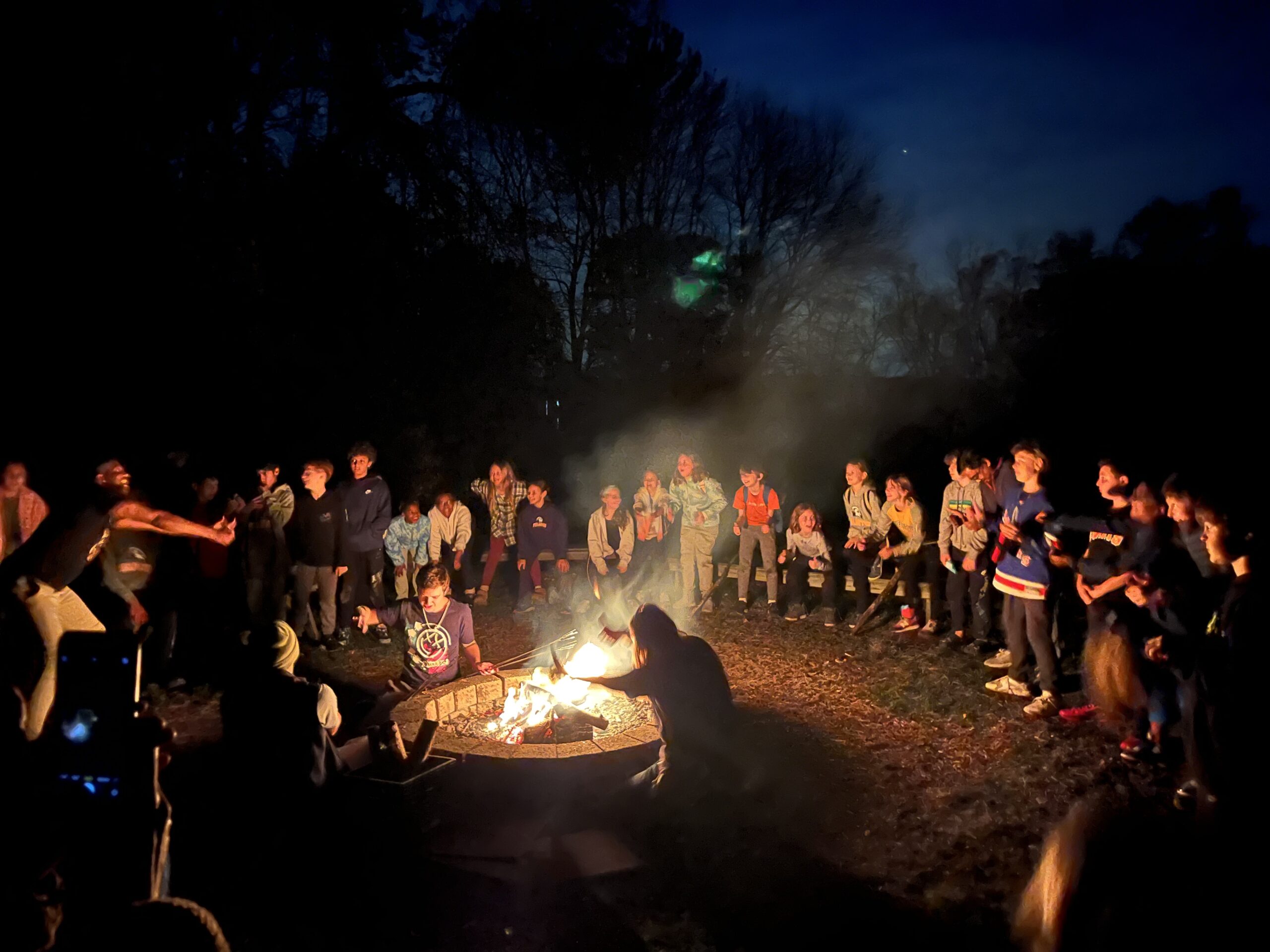 Students sit around firepit at night at Nature's Classroom.
