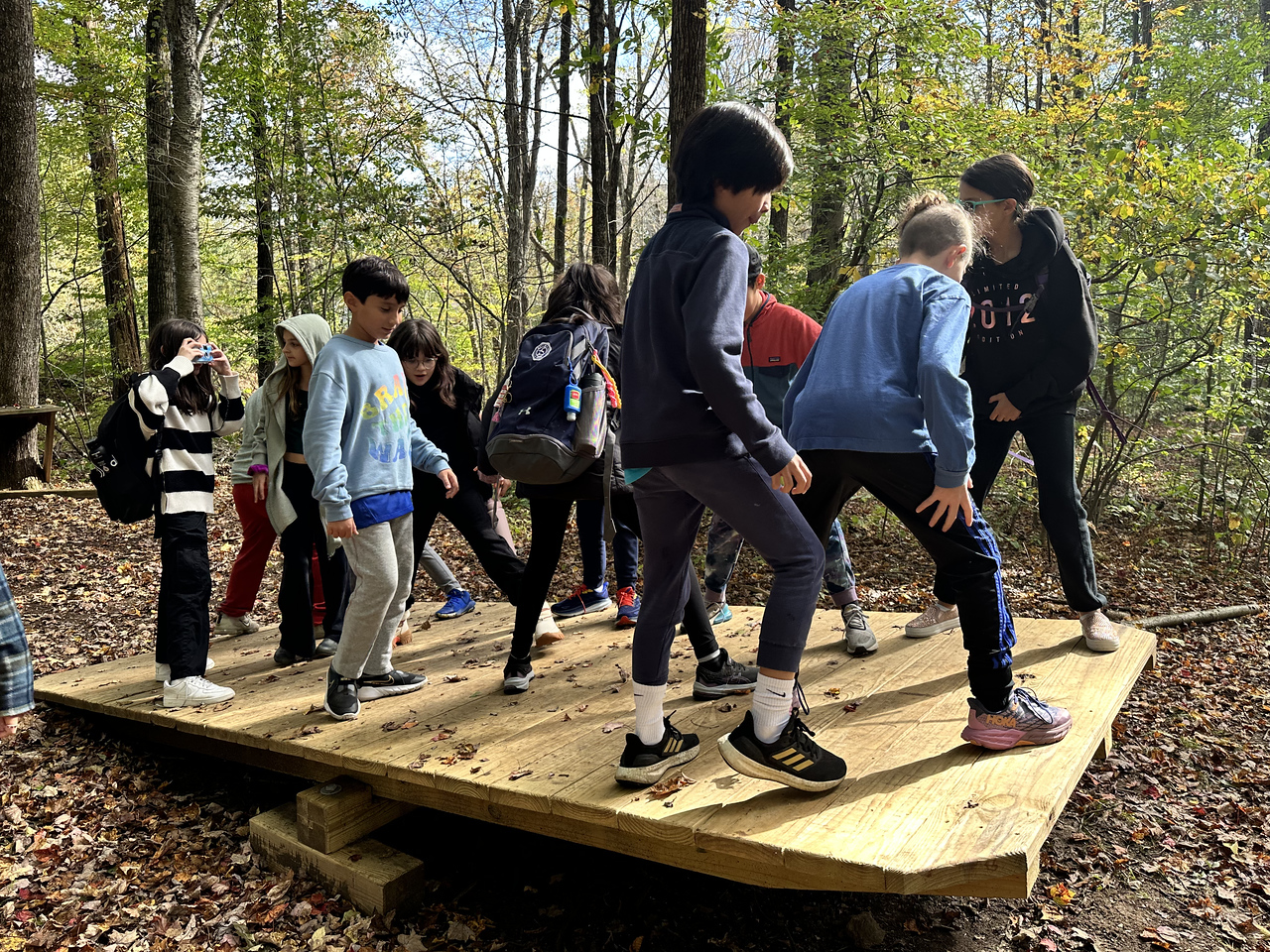 Students work together to complete ropes course challenge.
