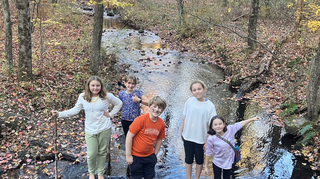 5th Graders cross stream using sticks in the woods at Nature's Classroom.