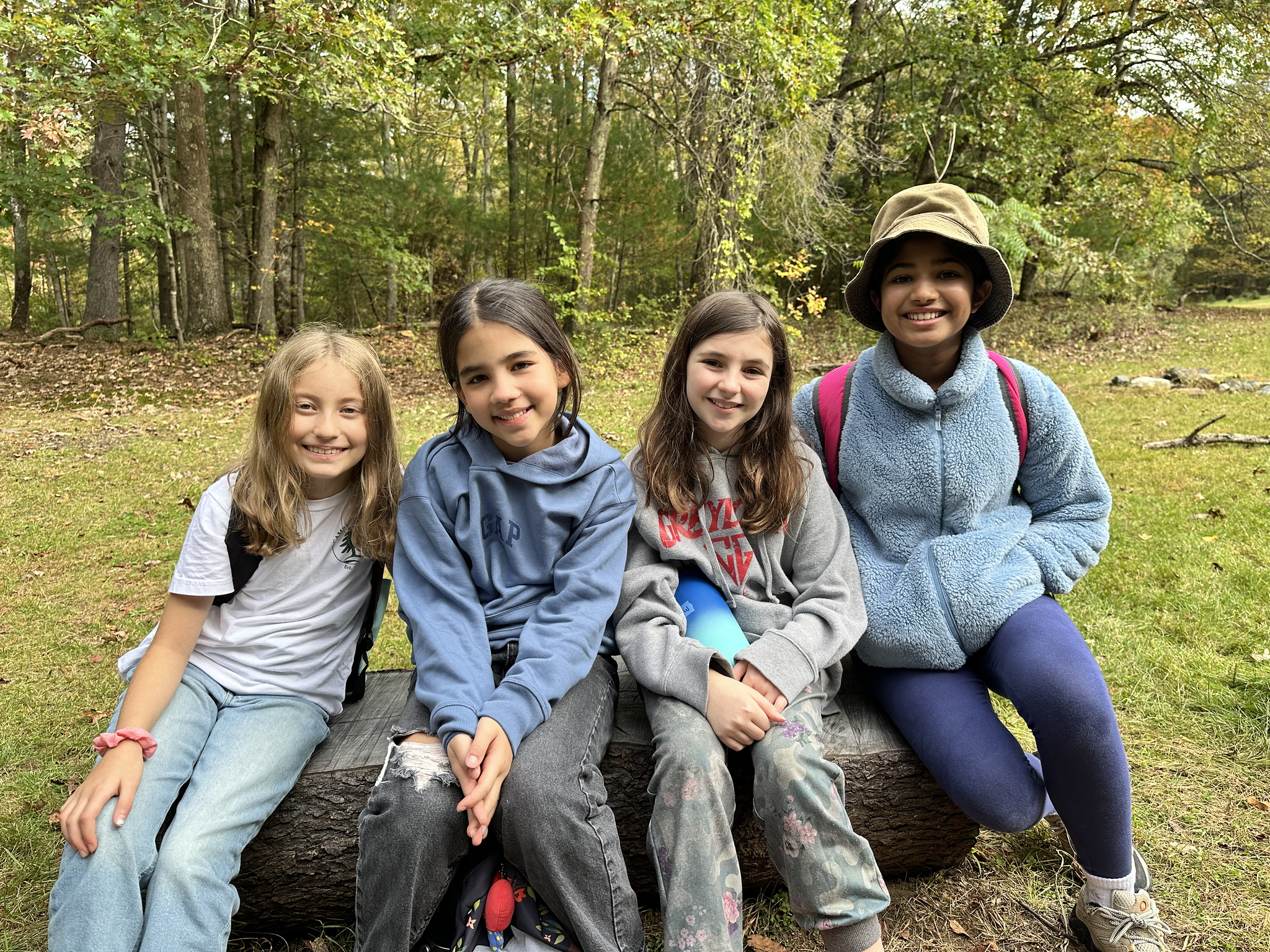 Ethical Culture students pose and smile around firepit.