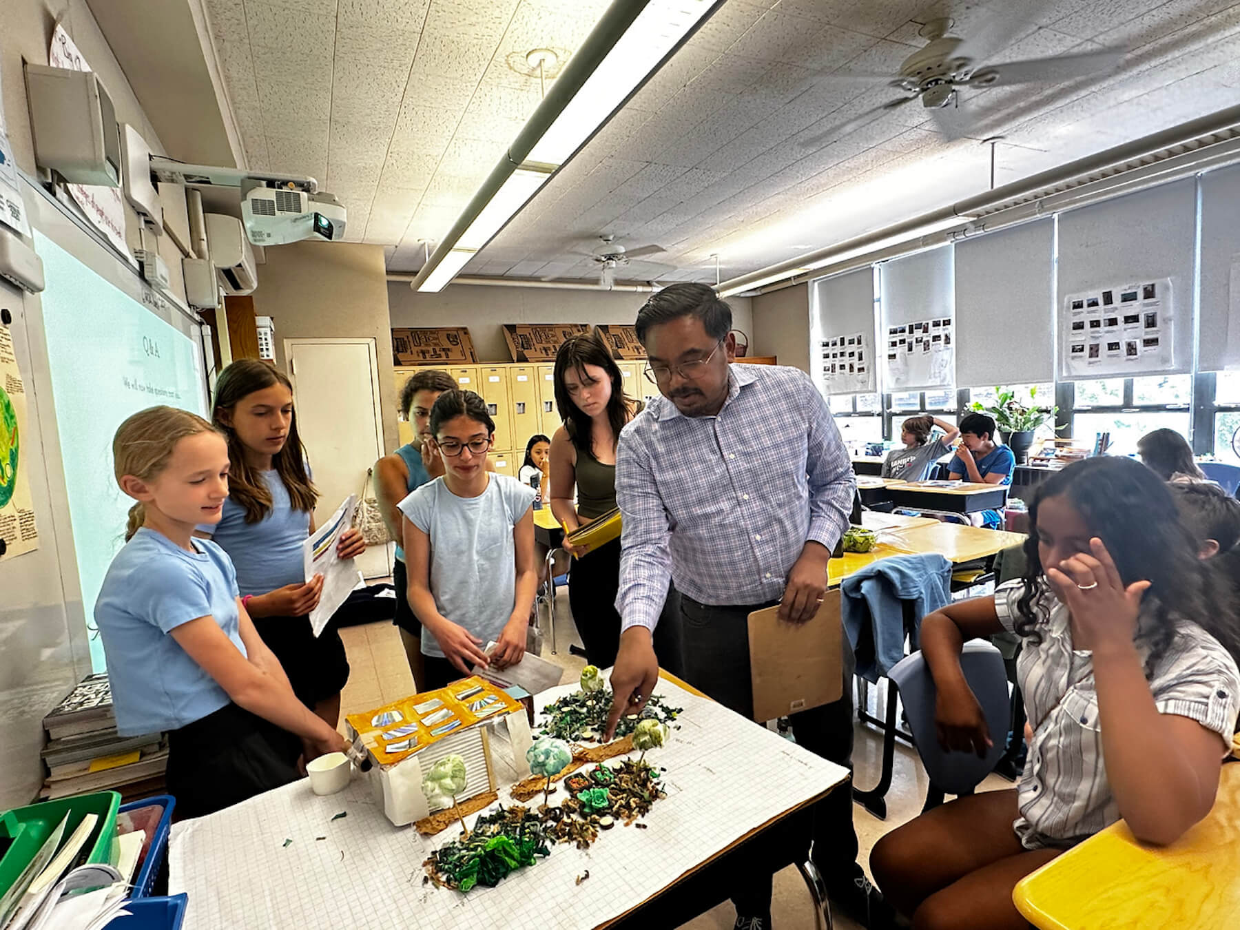 Assistant Principal Shawn Chisty observes Fieldston Lower students' Shark Tank project model.
