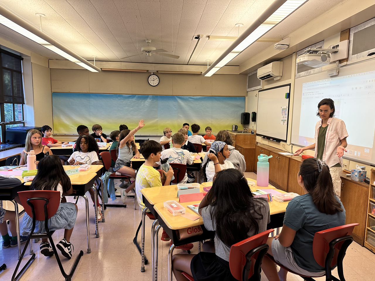 Fieldston Lower 5th Grade students sit at desks in classroom and listen to teacher at front of the class.
