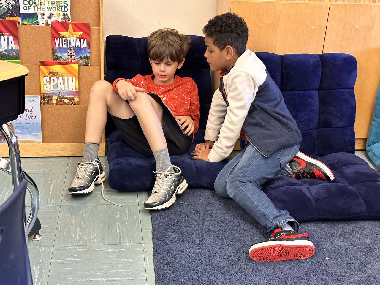 Two Fieldston Lower students read together on the floor in a classroom.