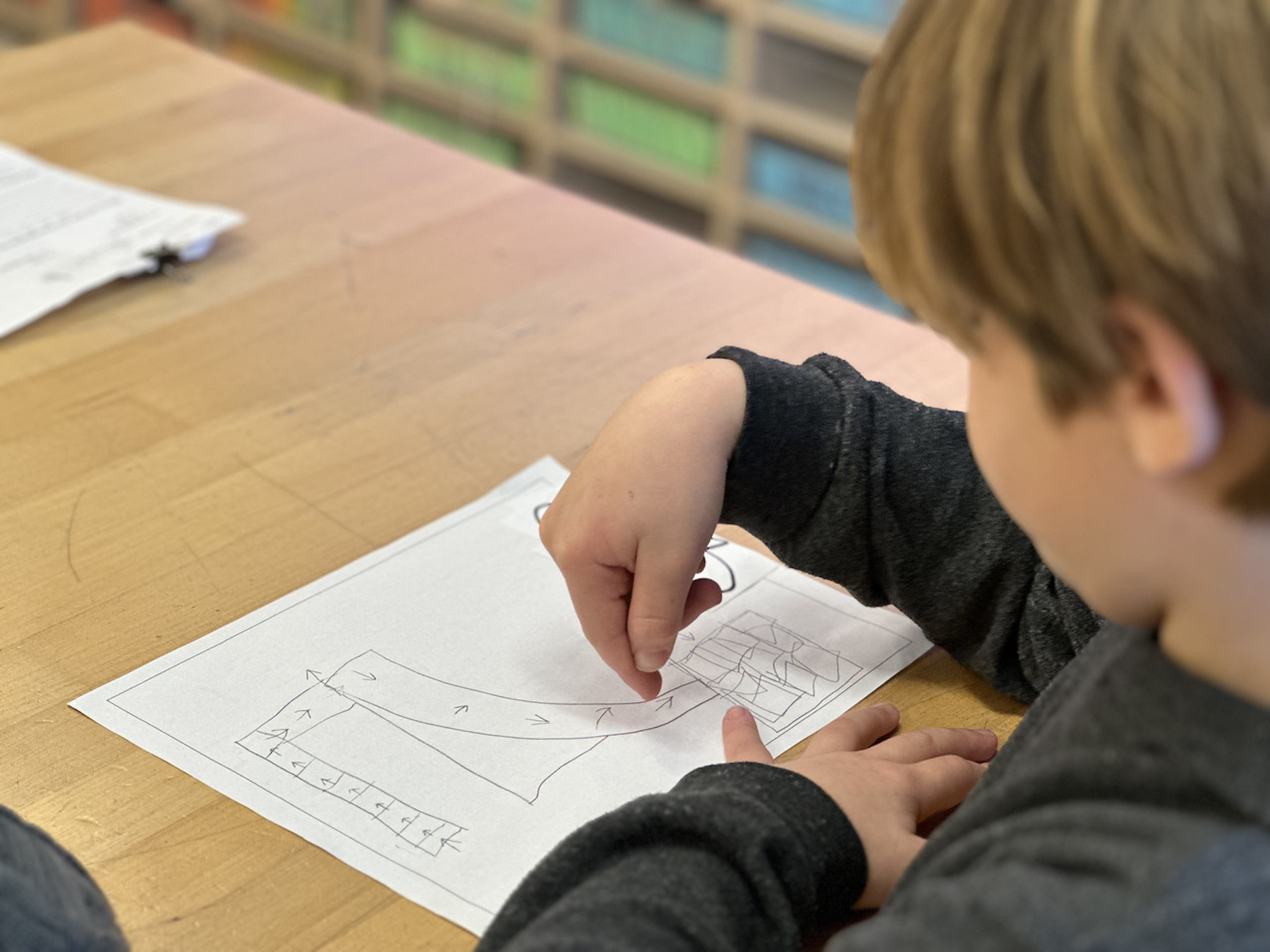Fieldston Lower student works on his storyboard at desk in classroom.