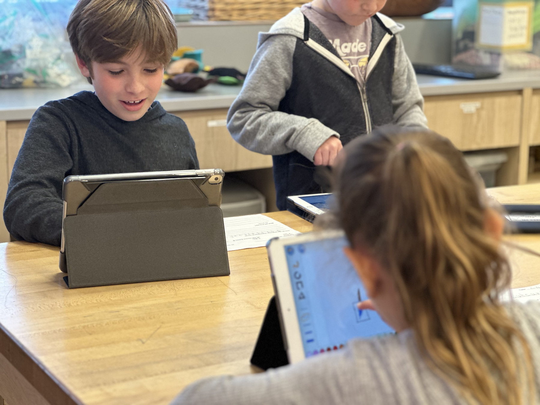 Group of three Fieldston Lower students work together on iPads in classroom.