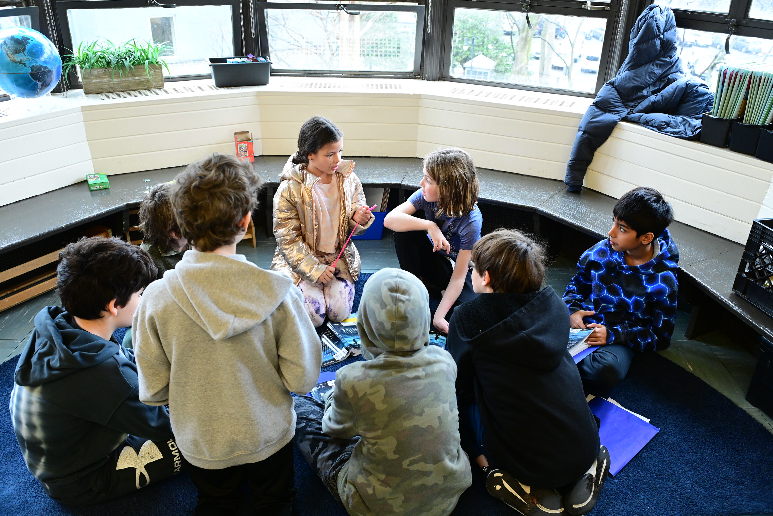 Fieldston Lower students sit on the floor in a classroom and engage in discussion about a text.