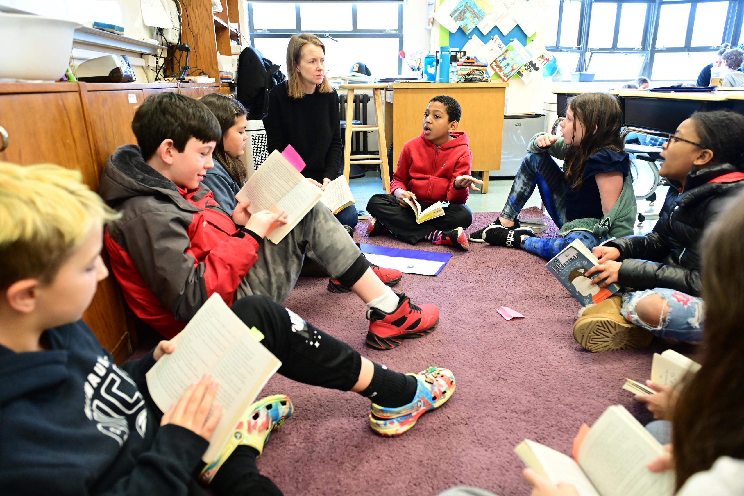 Fieldston Lower students sit in a circle on the floor and engage in discussion.