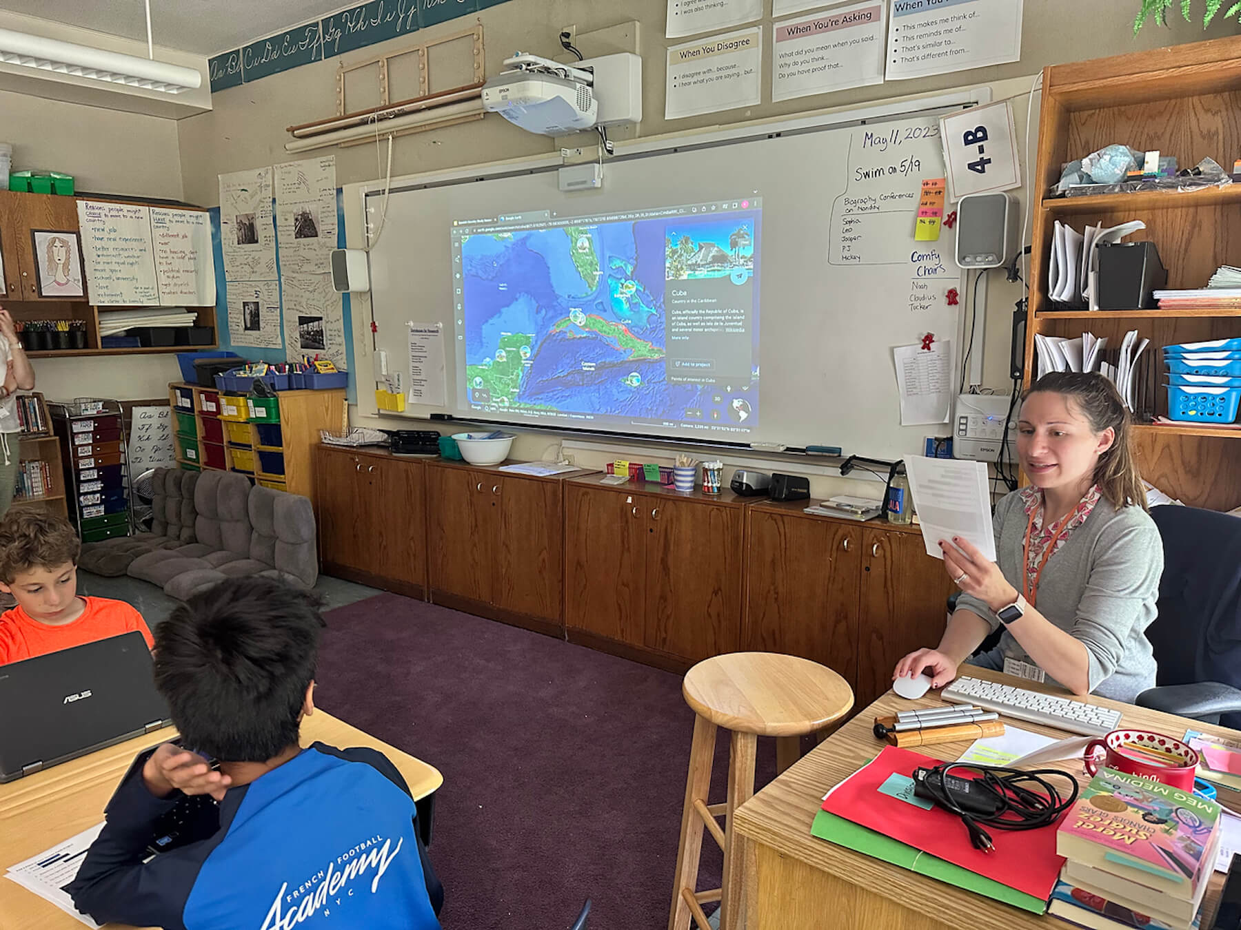 Kim Deveaux explains elements of Google Earth to Fieldston Lower students from her desk.