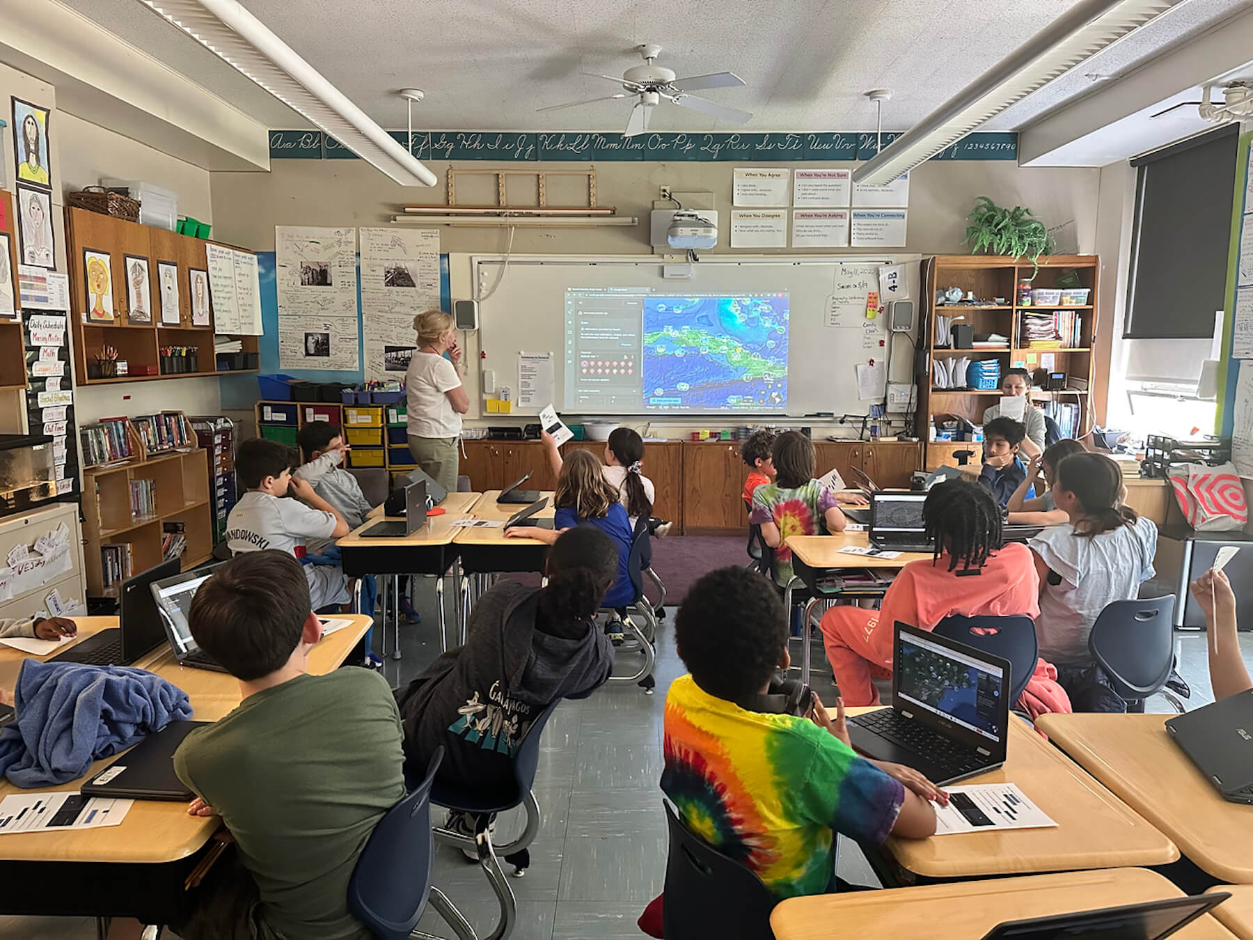 Fieldston Lower students look on from their desks as Cristina Mella demonstrates how to use Google Earth.