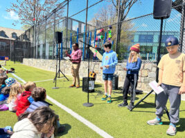 Fieldston Lower Assistant Principal Shawn Chisty speaks at Earth Day assembly on lower field. Other students stand nearby waiting to speak.