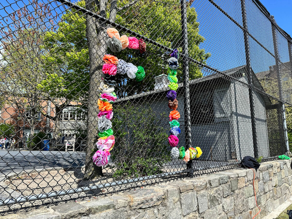 Fence decoration spelling out "FL" for Fieldston Lower using colorful flowers.