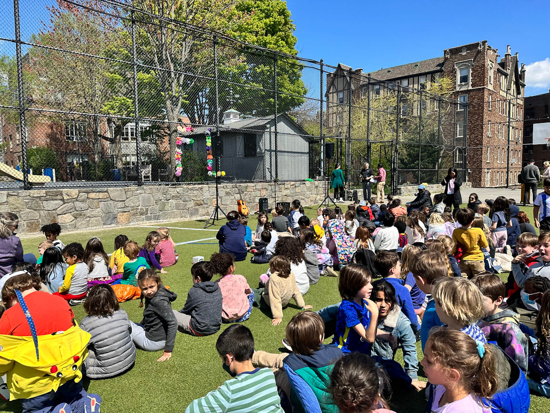 Fieldston Lower students sit on lower field waiting for Earth Day assembly for begin.