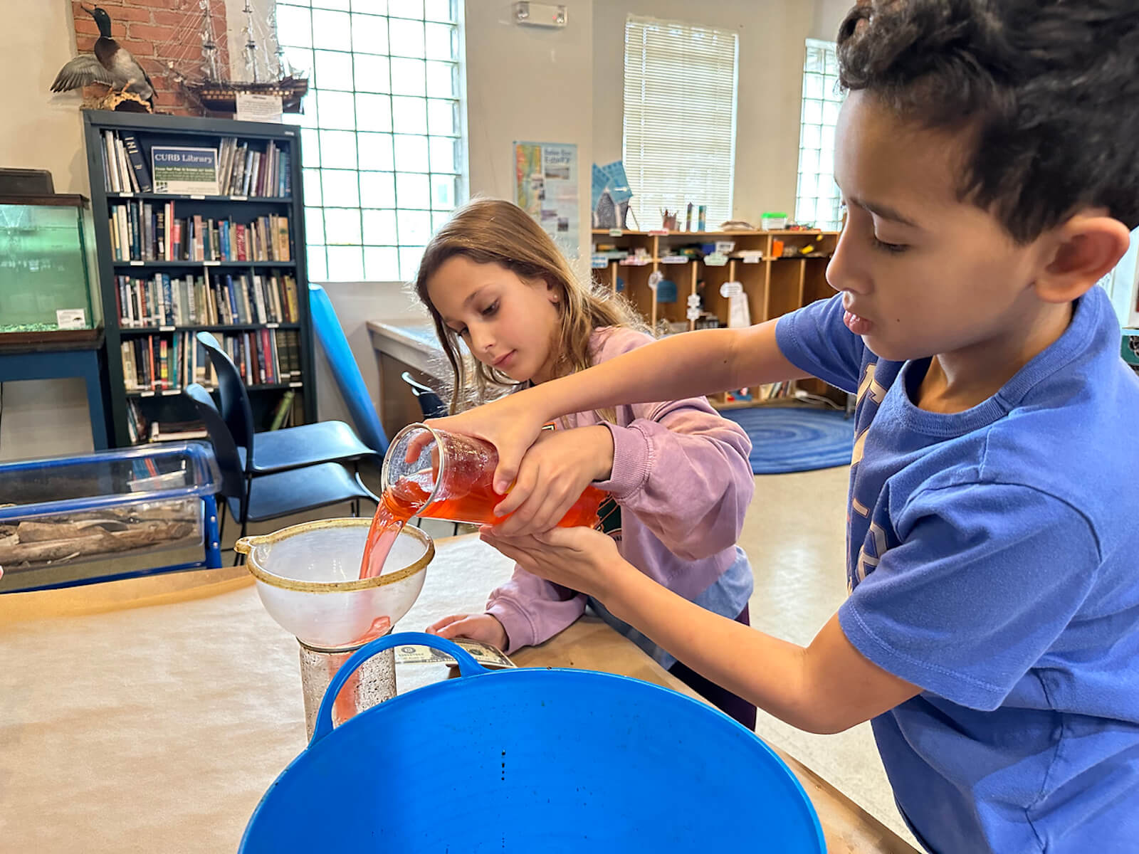 Two Fieldston Lower students pour water into a filter at the Beczak Center.