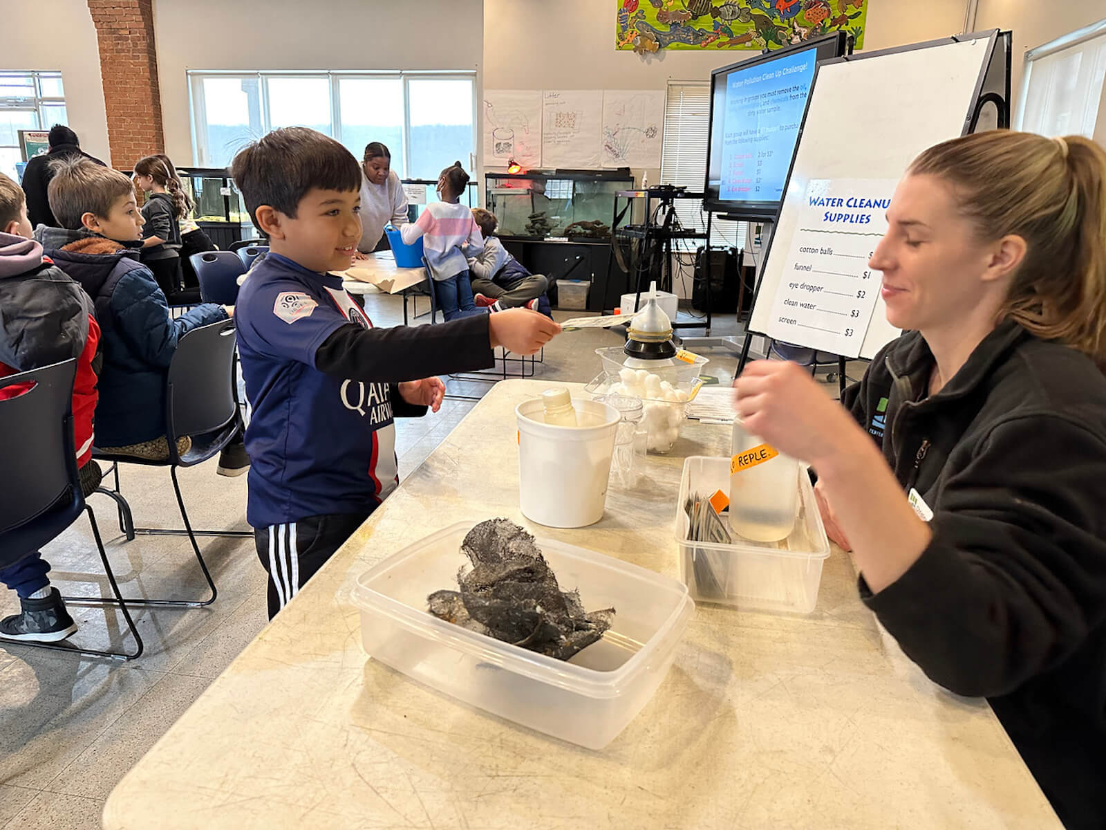 Fieldston Lower student pays for water cleaning materials at the Beczak Center.