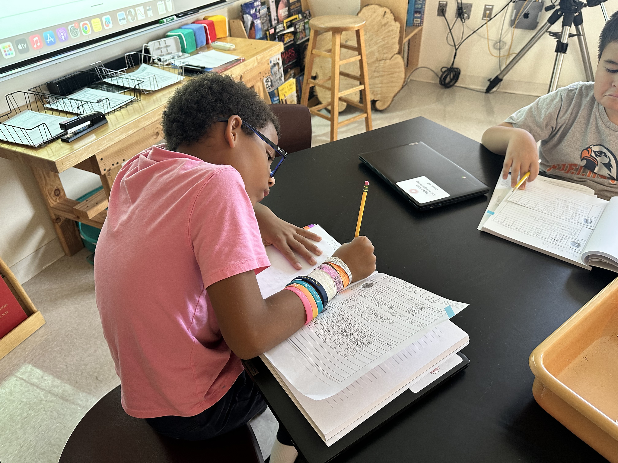 Student writes in lab notebook during Fieldston Lower moon lesson.
