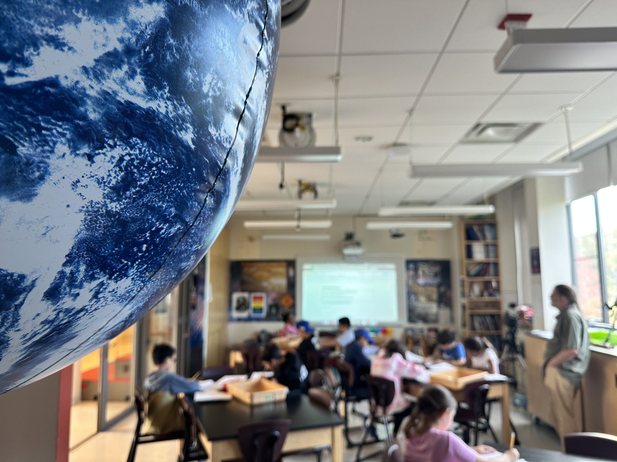 Photo of Earth model with students sitting in Fieldston Lower classroom in the background.