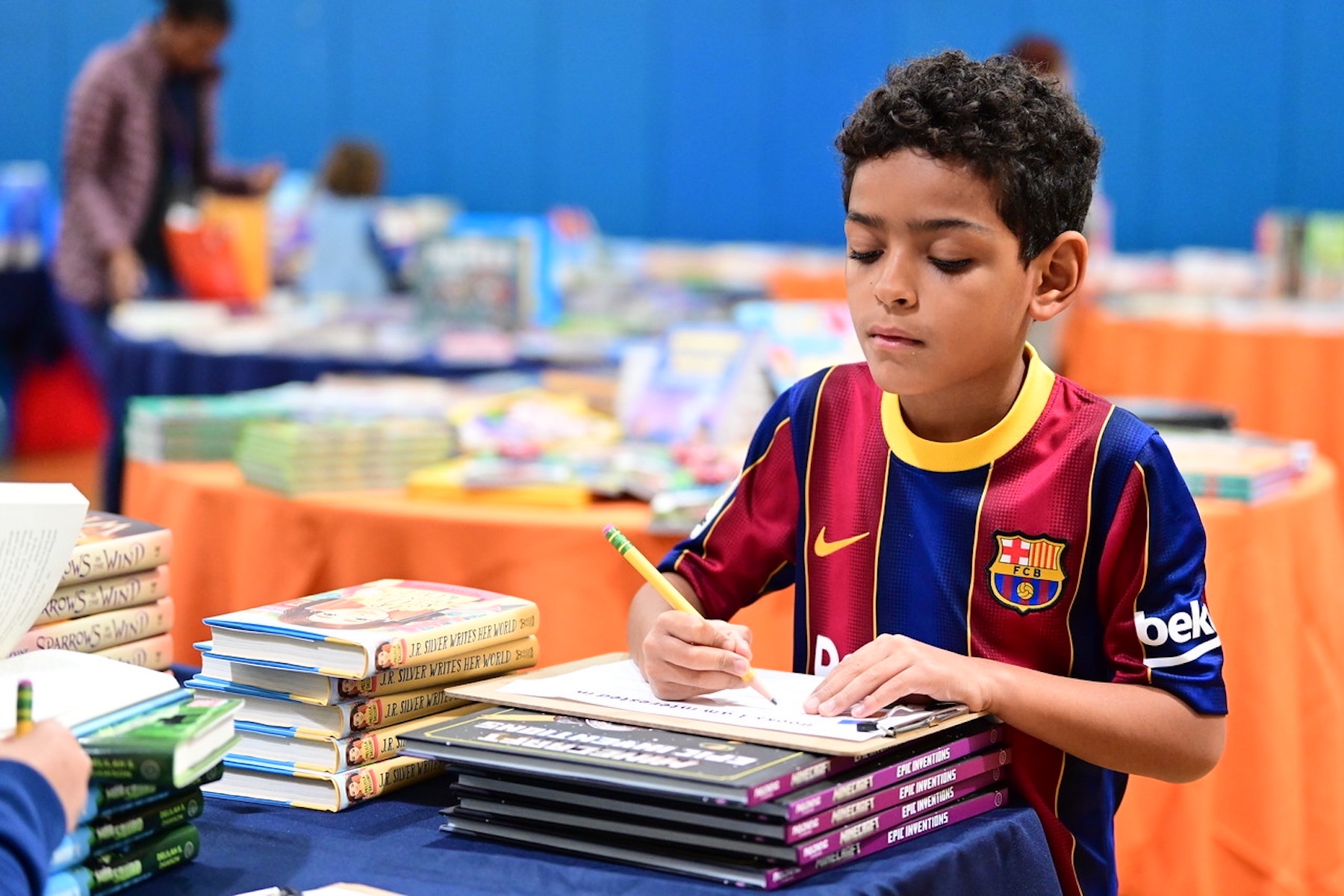 Fieldston Lower students writes down the name of a book using a pencil at the book fair.