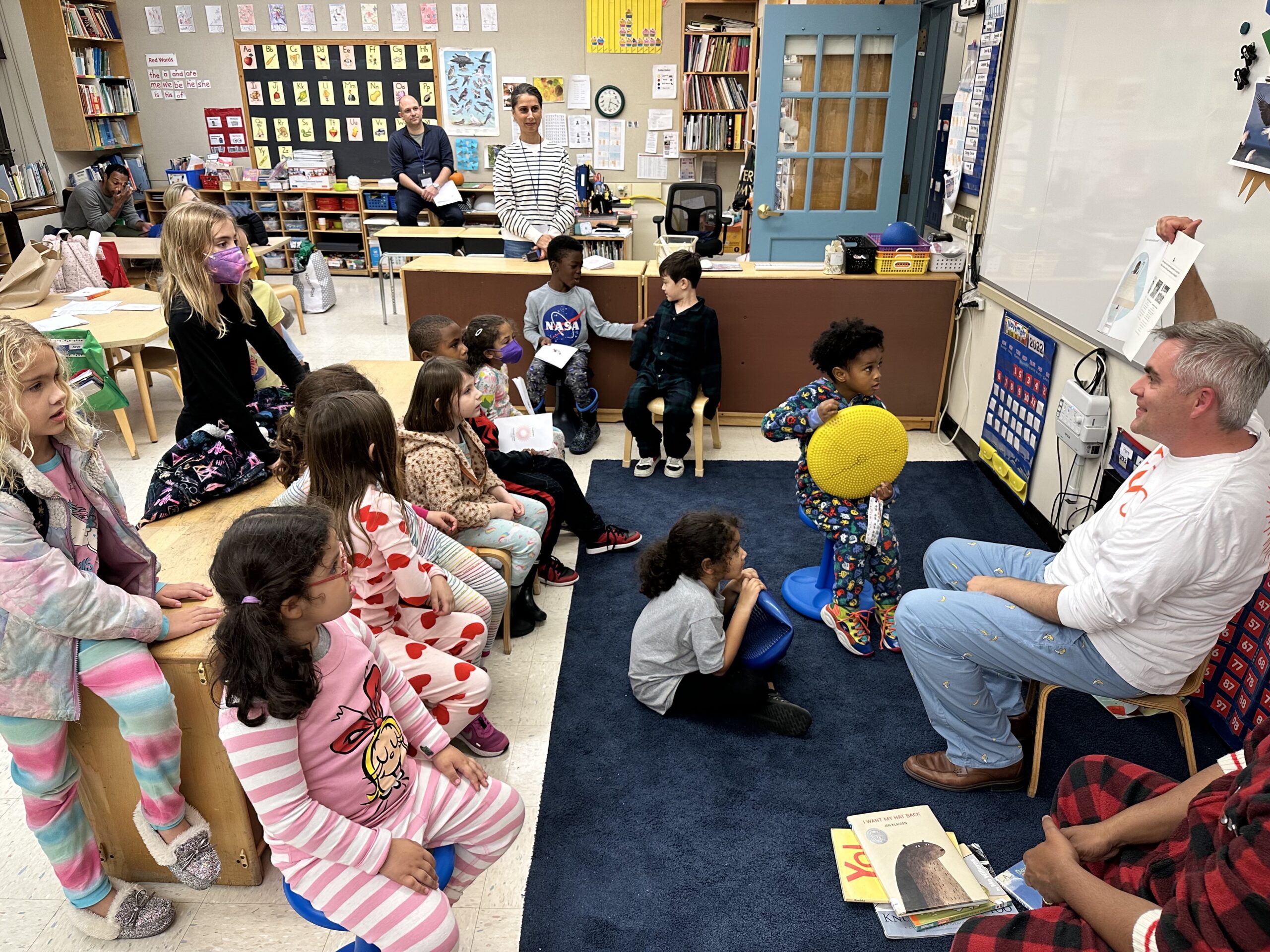 Fieldston Lower Principal Joe McCauley reads to a room full of students; they sit on the floor in pajamas and listen along.