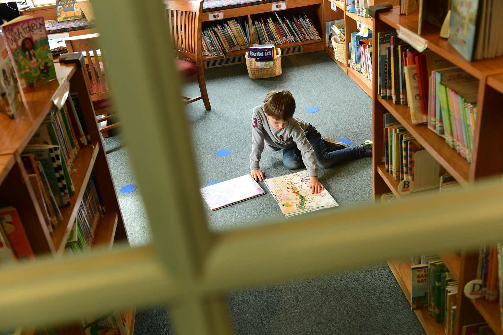 Student reads book while sitting on the floor in the Ethical Culture library.