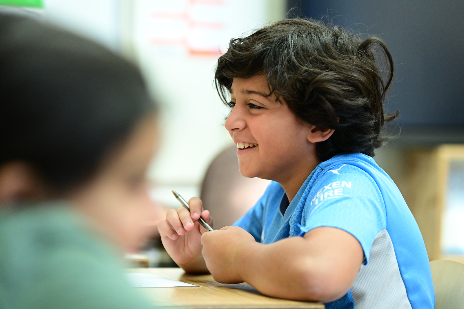 Ethical Culture student smiles at desk during language arts lesson. 