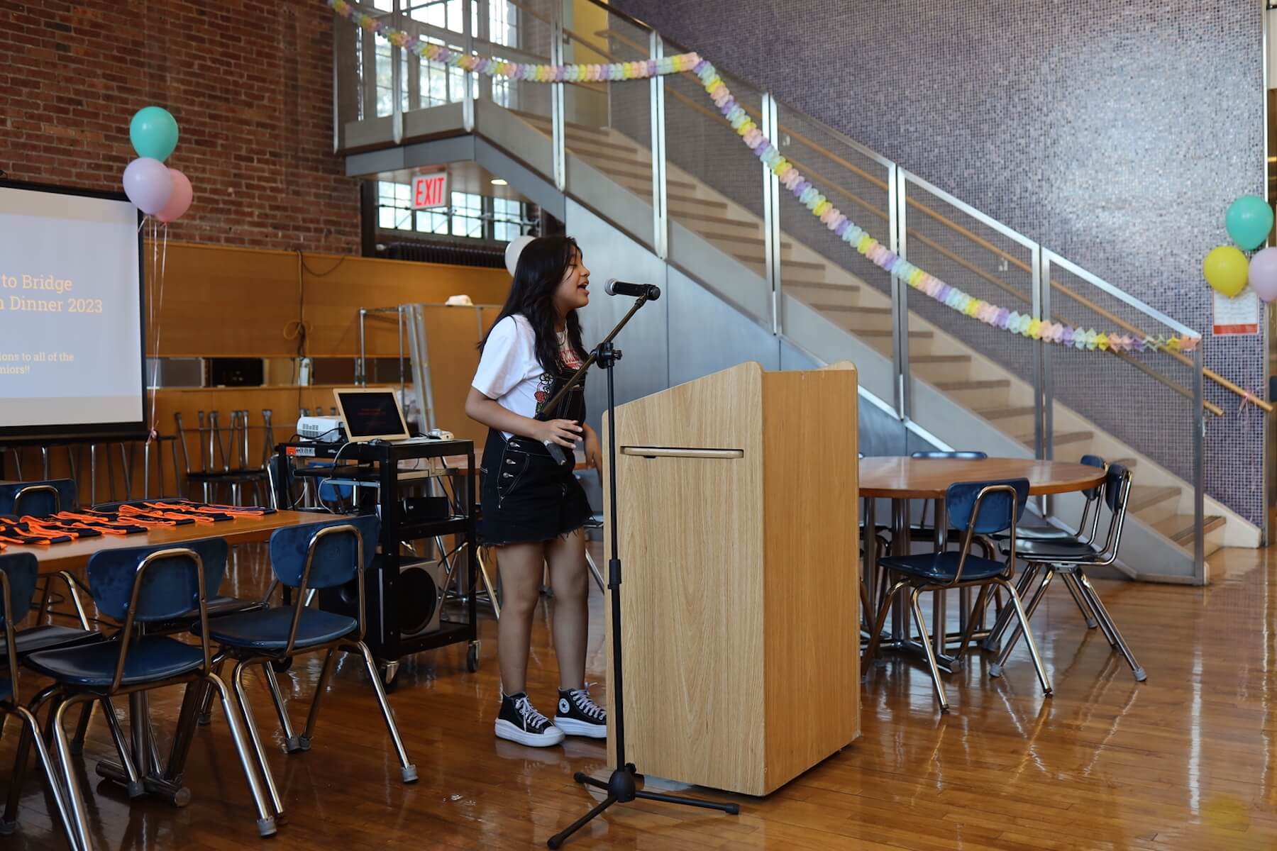 ECFS student speaks at podium at Bridge to Bridge year-end celebration in the Dining Hall.