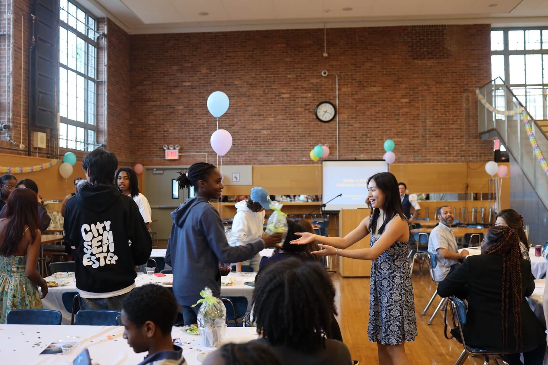 Fieldston Upper student hands potted plant to another student at Bridge to Bridge celebration.