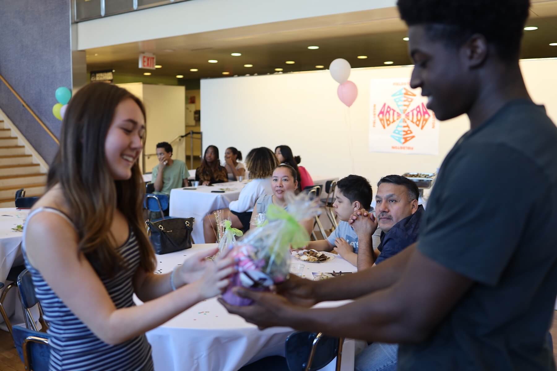 Fieldston Upper student hands potted plant to another student at Bridge to Bridge celebration.