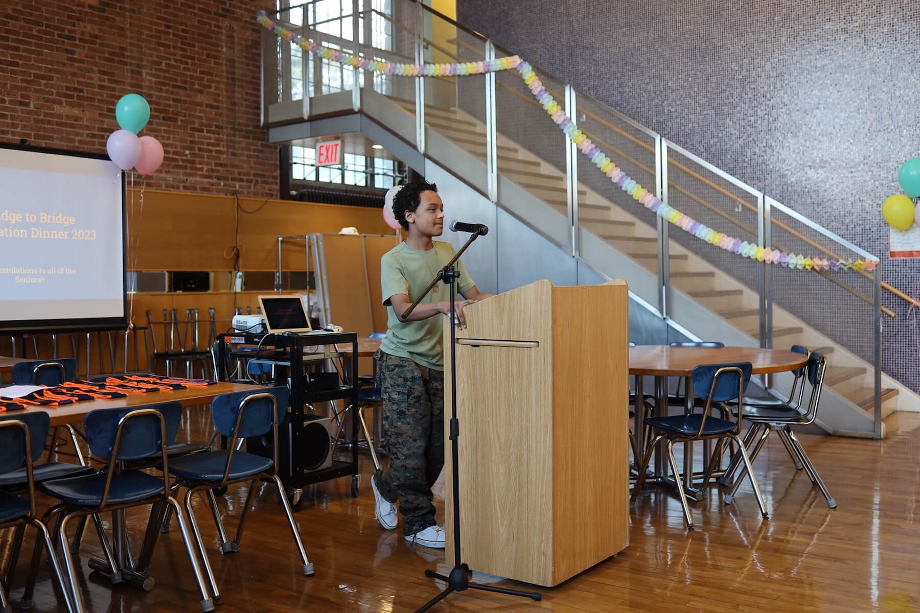 ECFS student speaks at podium at Bridge to Bridge year-end celebration in the Dining Hall.