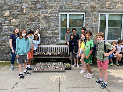 Students pose outside at Fieldston Middle in front of bench while working on science and ethics project.