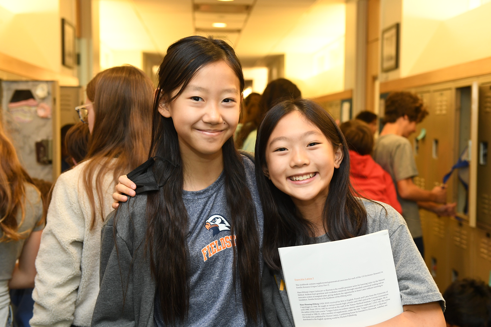 Fieldston Middle students smile and pose in school hallway with a copy of a paper related to their project. 