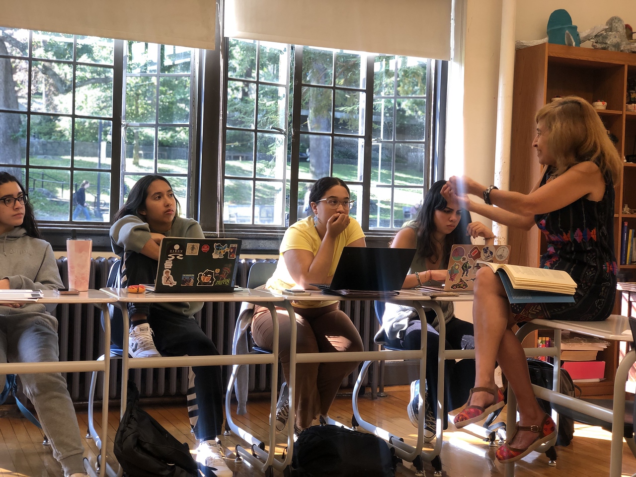 Students are engaged in discussion as Lorena Rodas-Ramirez, Spanish teacher, speaks to them in a Fieldston Upper classroom.