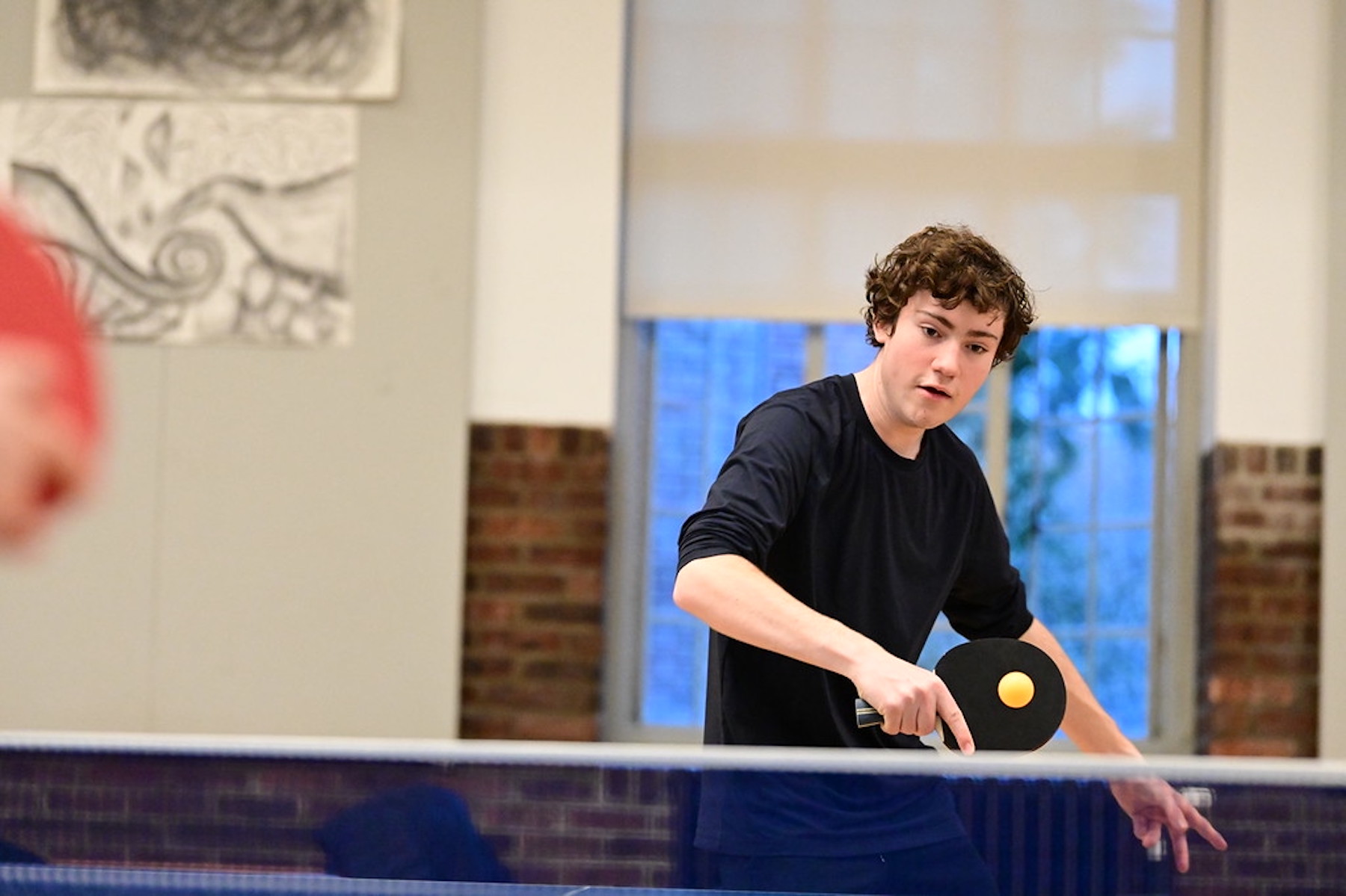 Fieldston Upper student practices table tennis in the Student Commons.