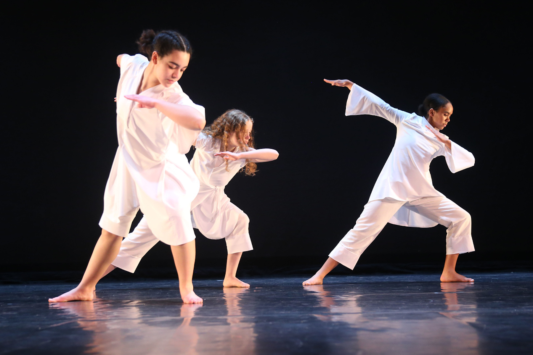 Three Fieldston Upper dancers perform wearing all white.