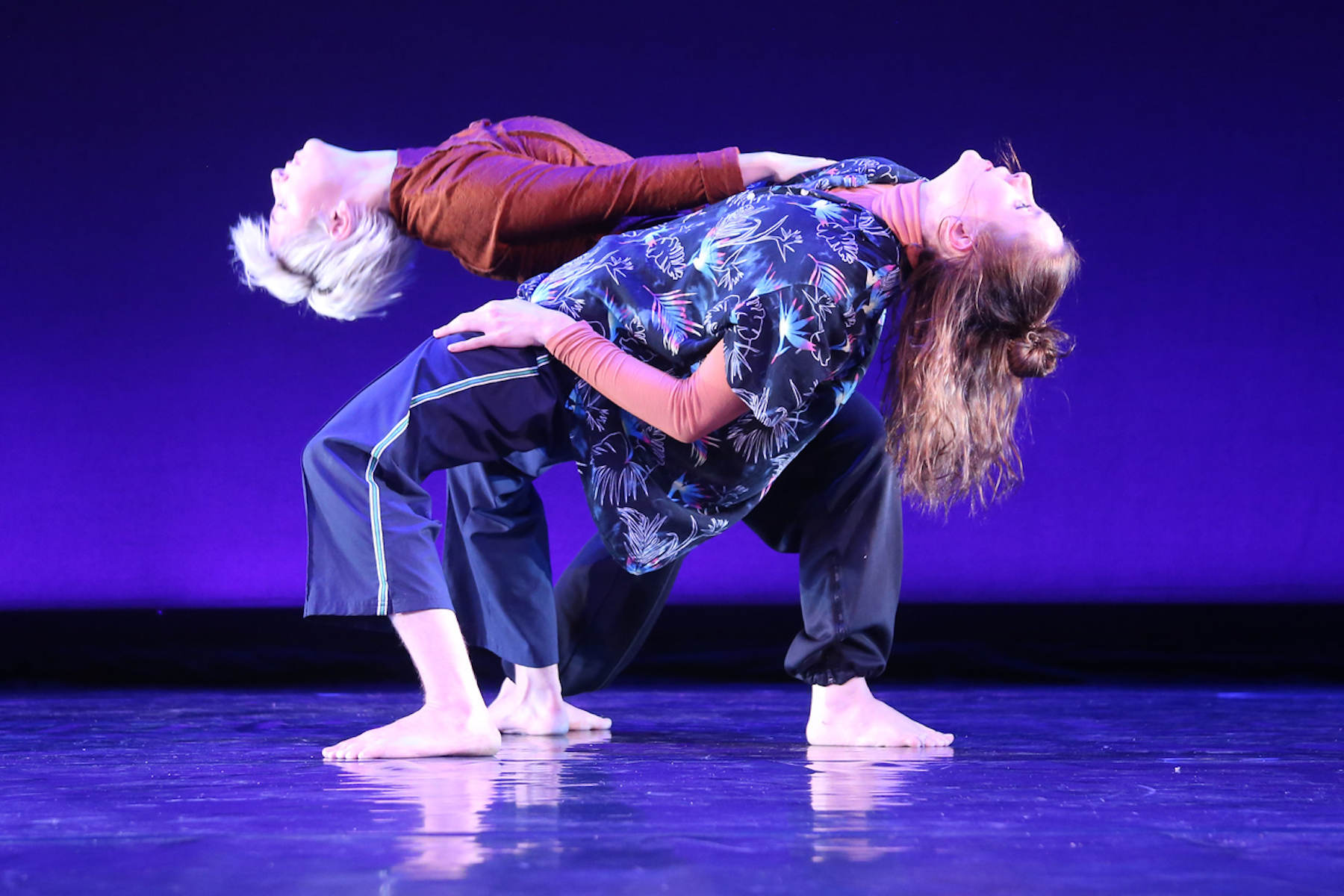 Two David Dorfman dancers perform on stage.