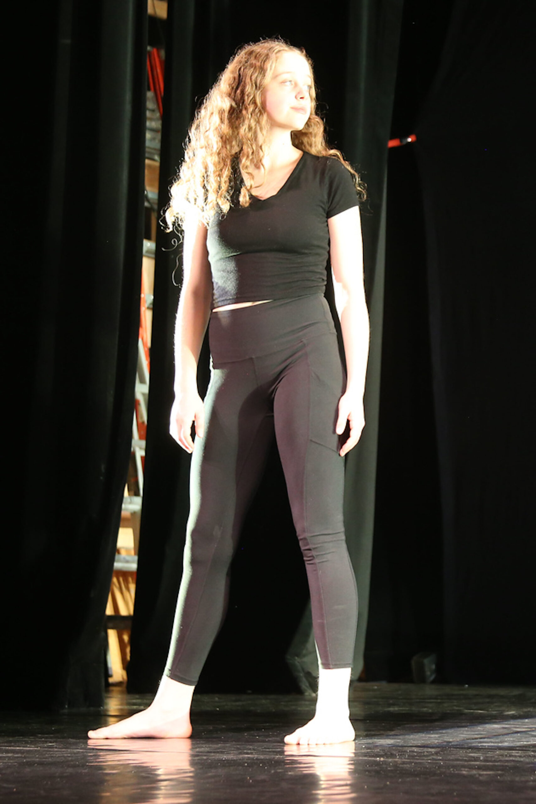 Fieldston Upper student performs on stage; she stands still, arms by her side, looking out toward the audience.