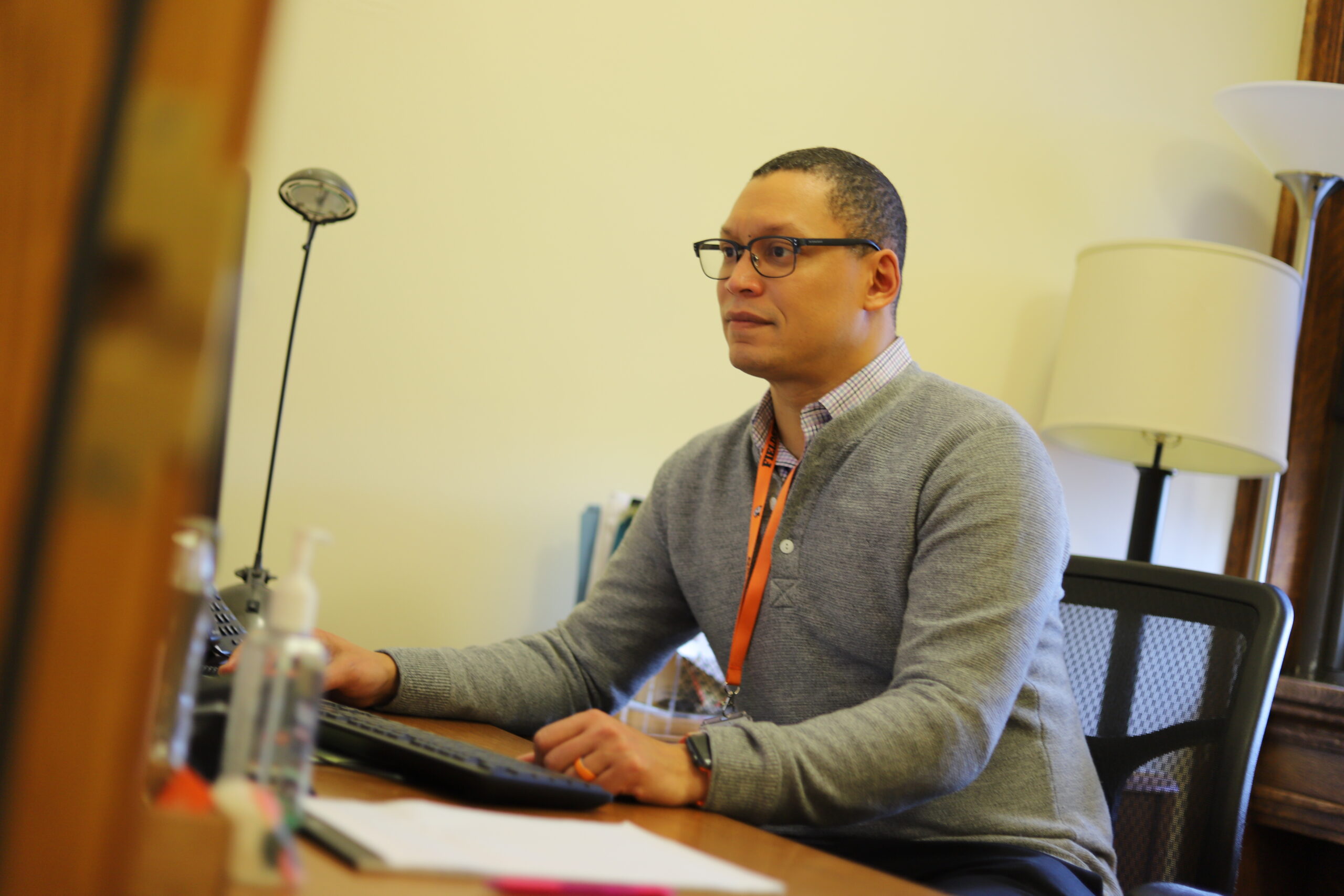 Director of Enrollment Management Charles Guerrero sits at his desk, looking at a computer
