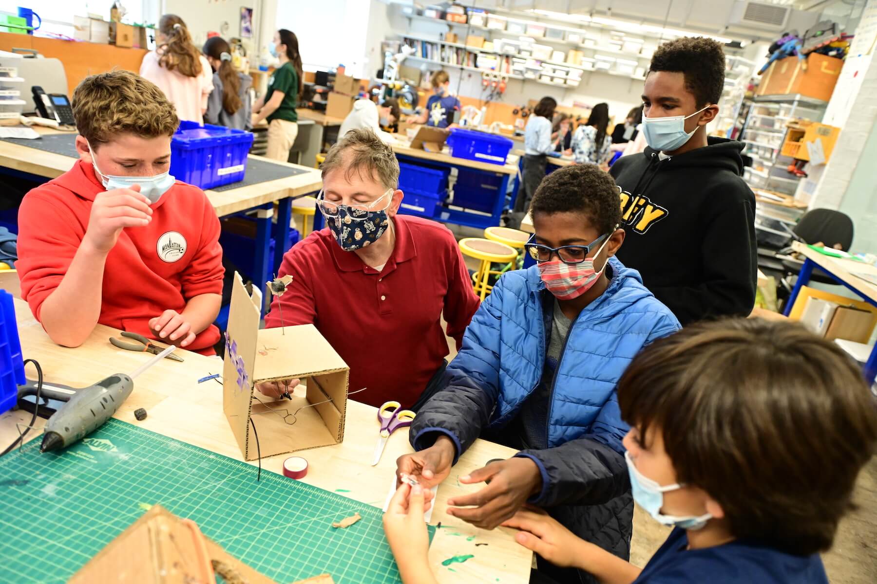 Ethical Culture Fieldston School Fieldston Middle students gather around a work table to build project with cardboard
