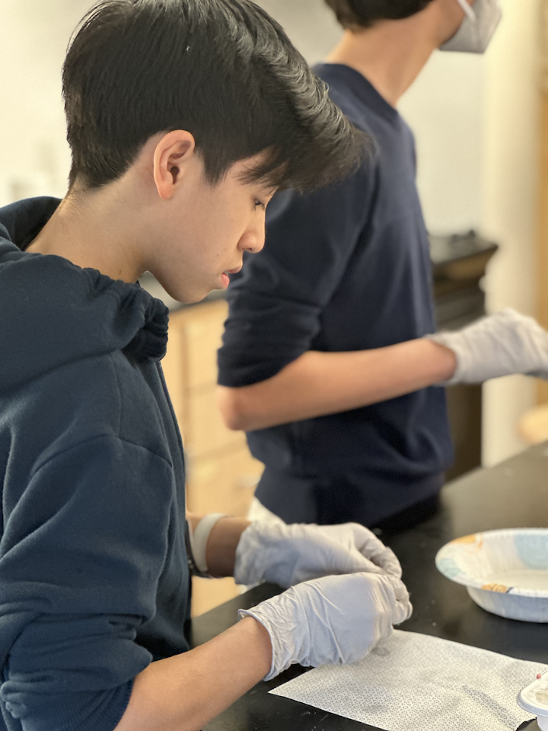 Student works diligently to fill dumpling at desk.