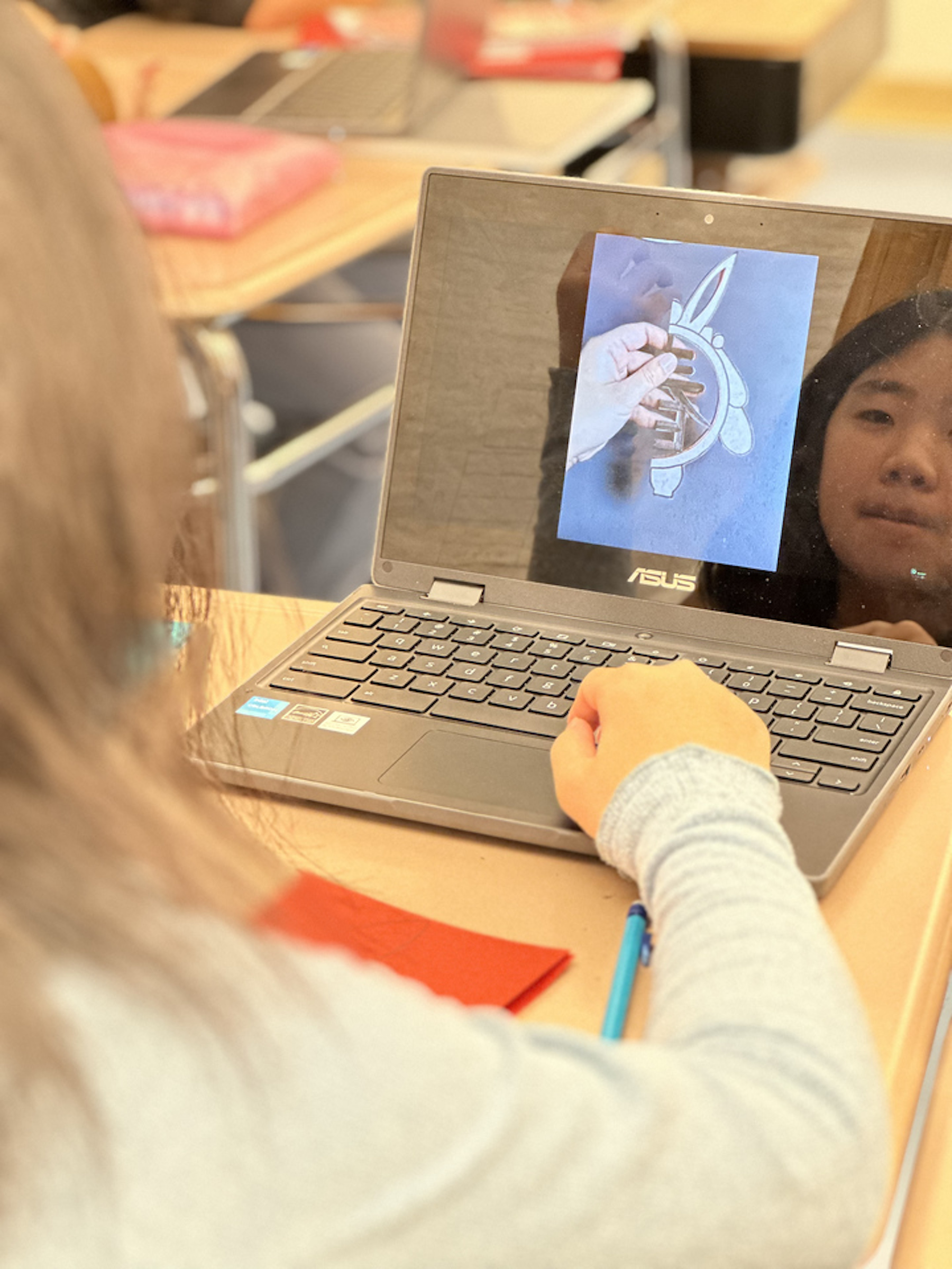 Student looks at computer tutorial about creating paper cutouts.