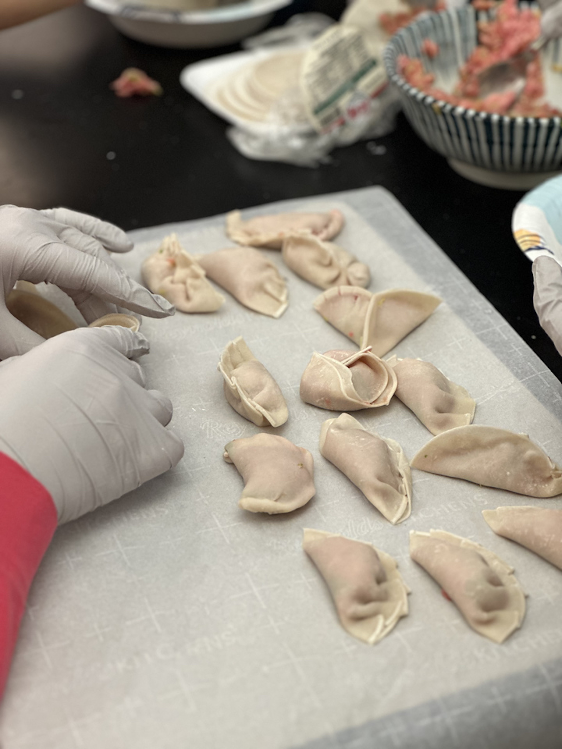 Several dumplings made by Fieldston Middle students rest on piece of parchment paper.