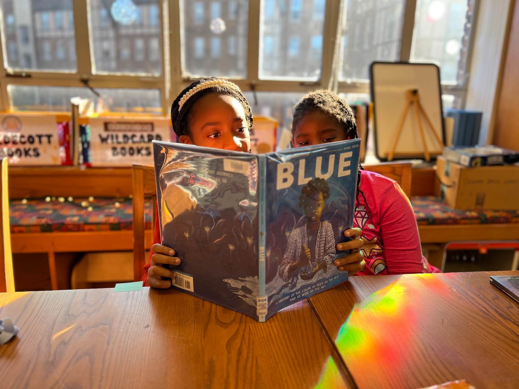 Ethical Culture Fieldston School Fieldston Lower students sit together reading at at table in the library