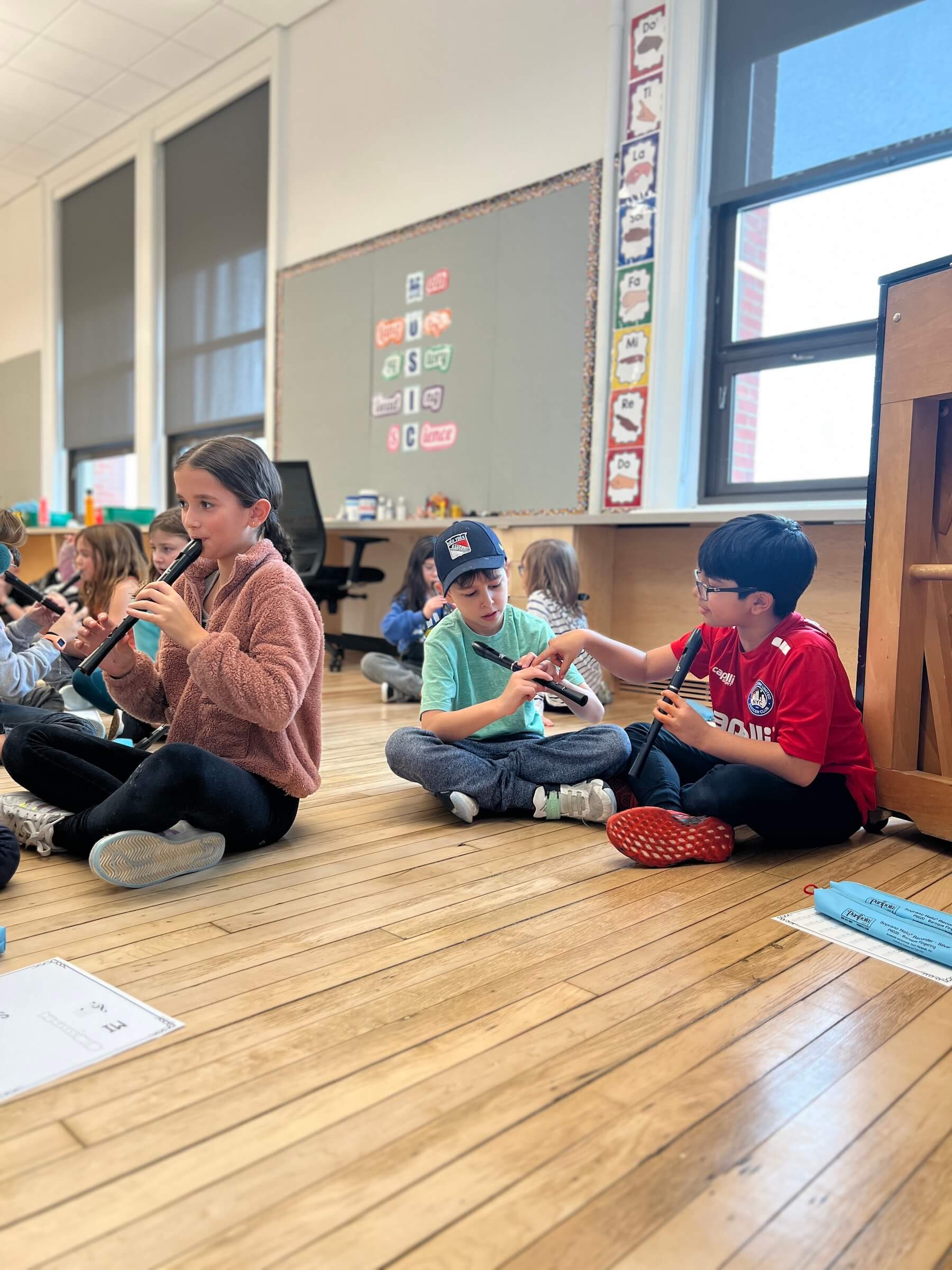 Ethical Culture Fieldston School's Ethical Culture students sit on the classroom floor to play their recorders together.