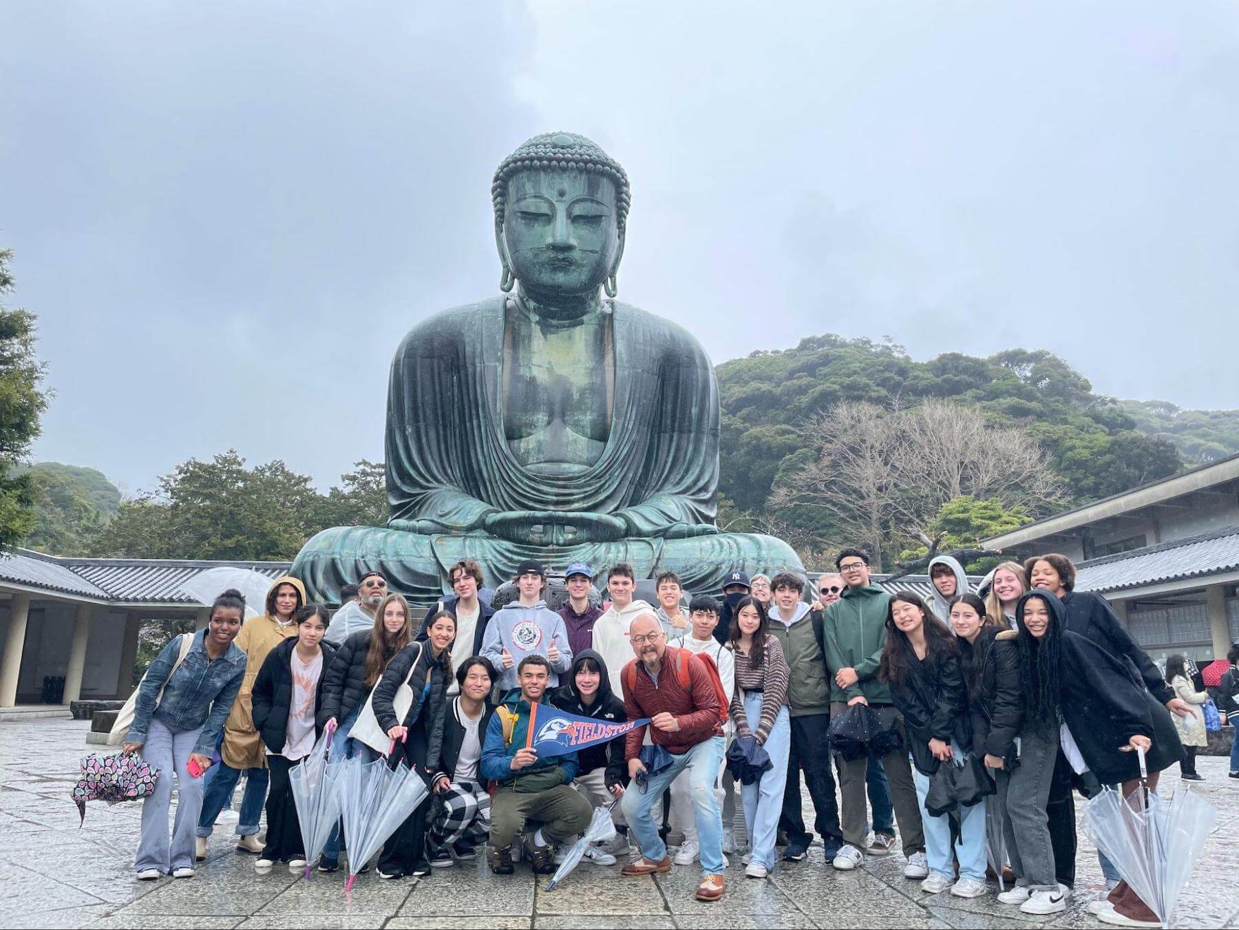 A group of Ethical Culture Fieldston students pose in front of a Buddha statue in Japan