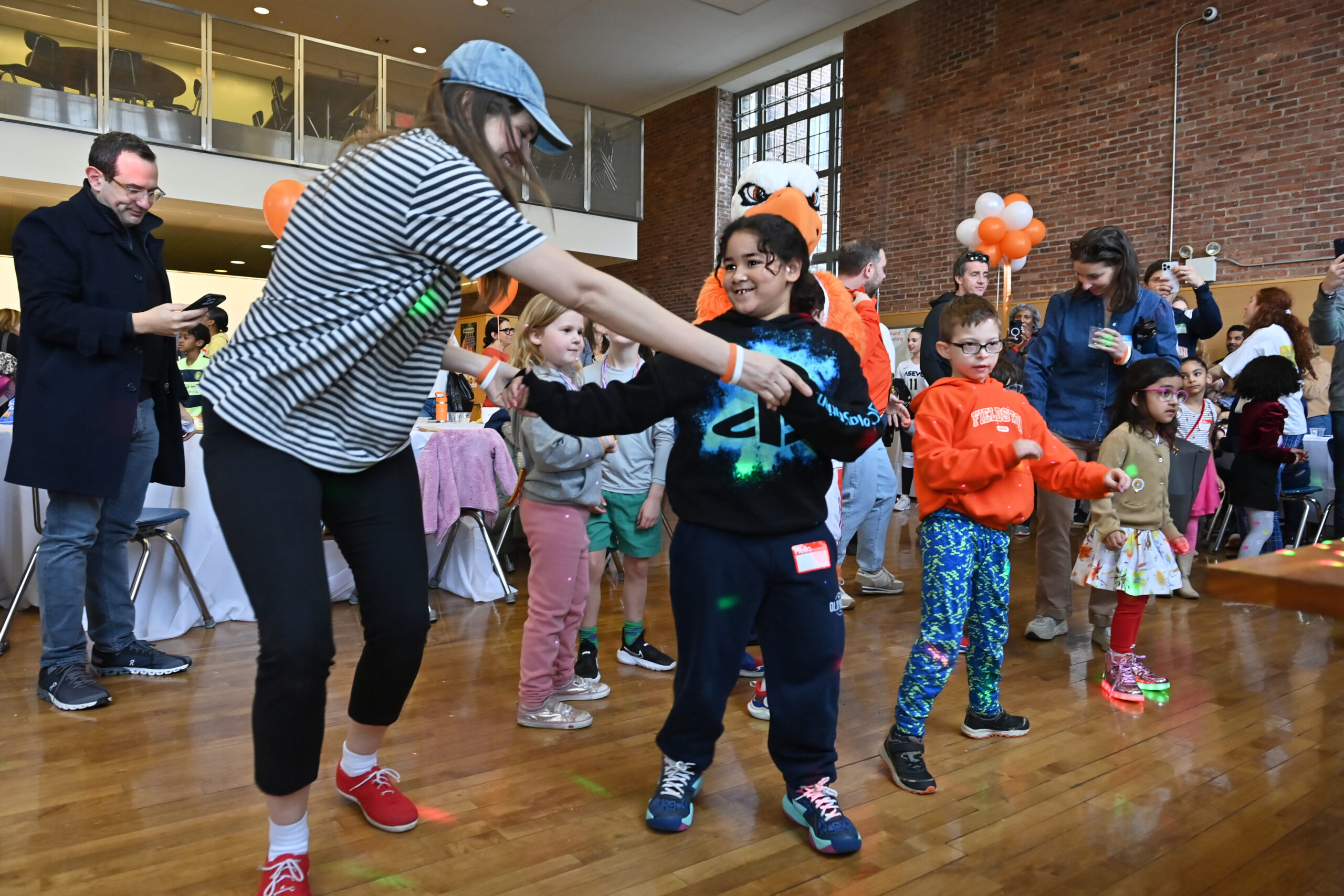 Students and adults dance happily on the dance floor