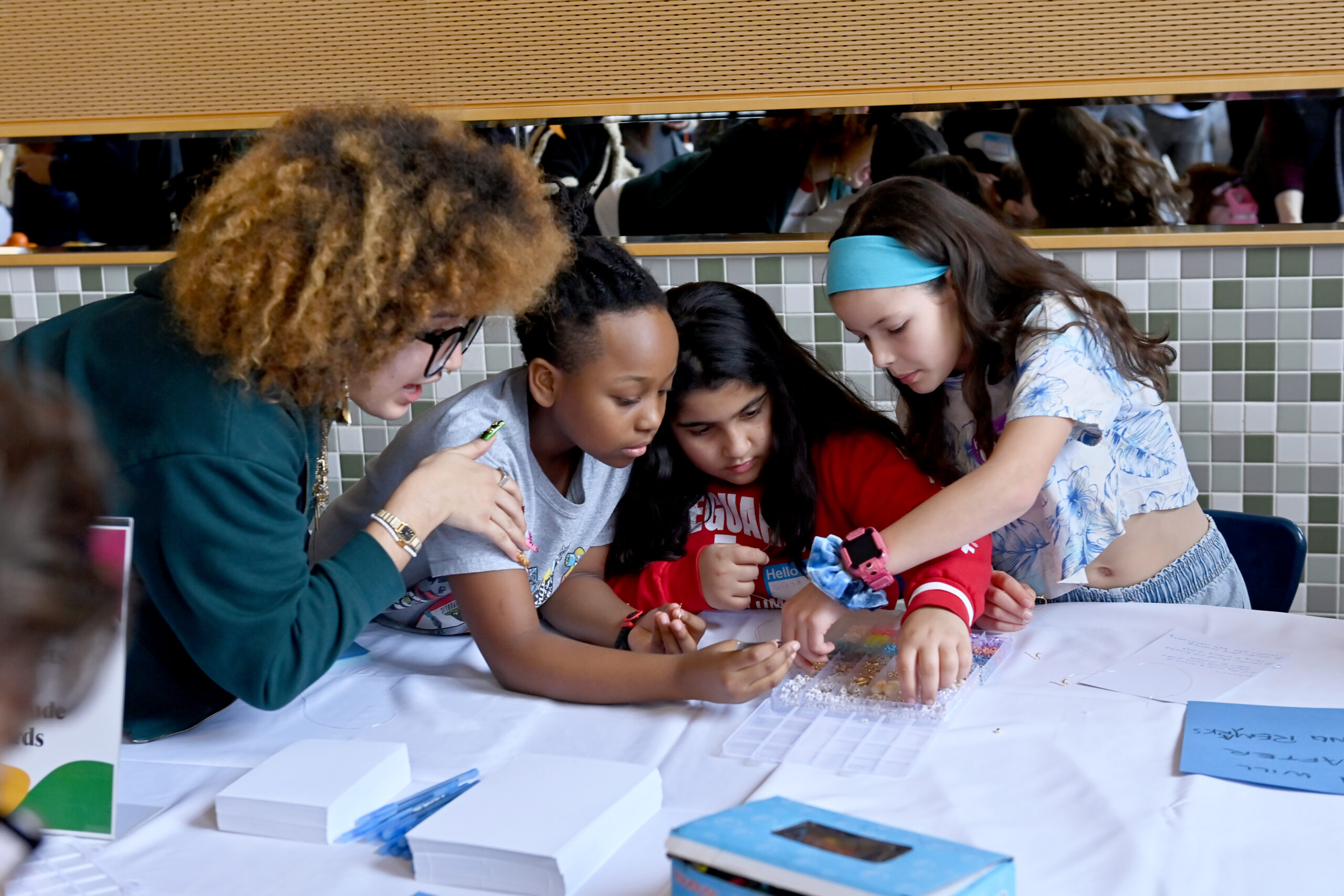 A group leans in close to look at beads in a small carrying case
