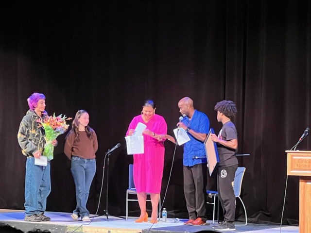 Dr. Elizabeth Alexander receiving presents on stage from Dr. Alwin Jones and several students