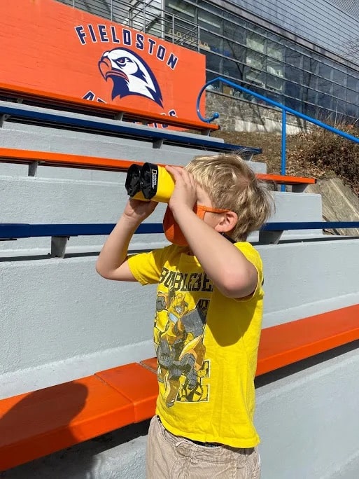 Student bird watching on bleachers